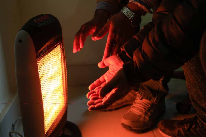 People tires to rid of cold by sitting infront of electric heater